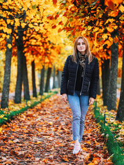Beautiful young woman walks in autumn Park in November. maple alley