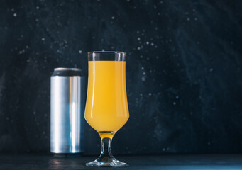 A glass of sour craft citrus beer on a dark background with copy space .
