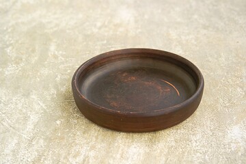 Empty brown clay plate or tray on gray concrete background.