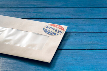 Envelope with voting ballot papers sent by mail for absentee vote in presidential election. Blue wooden table with copy space