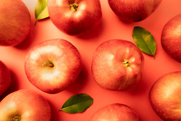 Red apples and leaves on a red background. Bright poster.