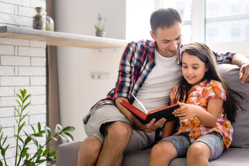 Obraz premium a young father with his little daughter reads the Bible