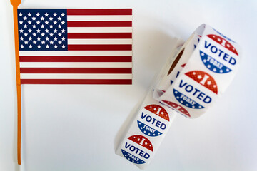 Roll of I Voted Today stickers and USA flag on white background. US presidential election concept