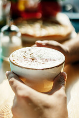 a Cup of coffee with foam in the hand of a man in a cafe