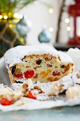 Dresden Christmas Stollen with raisins, dried apricots, dried cherries, nuts and candied fruits in sugar glaze on a festive background. Delicious festive Christmas dessert.