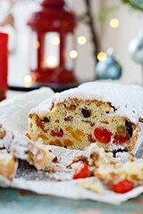 Dresden Christmas Stollen with raisins, dried apricots, dried cherries, nuts and candied fruits in sugar glaze on a festive background. Delicious festive Christmas dessert.