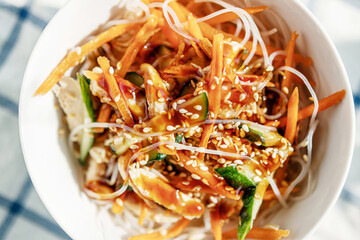 rice noodles with vegetables and chicken in a round plate natural sunlight in a cafe