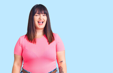 Young plus size woman wearing casual clothes winking looking at the camera with sexy expression,...