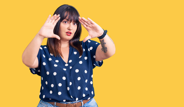 Young plus size woman wearing casual clothes doing frame using hands palms and fingers, camera perspective