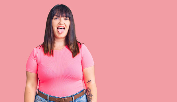 Young plus size woman wearing casual clothes sticking tongue out happy with funny expression. emotion concept.