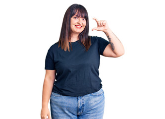 Obraz na płótnie Canvas Young plus size woman wearing casual clothes smiling and confident gesturing with hand doing small size sign with fingers looking and the camera. measure concept.