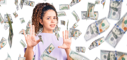 Beautiful kid girl with curly hair wearing casual clothes afraid and terrified with fear expression stop gesture with hands, shouting in shock. panic concept.