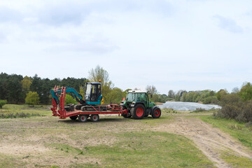 Obraz premium Tractor and trailer with excavator in the nature reserve Amsterdamse Waterleidingduinen for landscaping