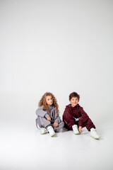 curly long-haired girl and boy in tracksuits on a white background