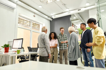 Cheerful young team greeting new employees, Aged man and woman, senior interns shaking hands with colleagues in the modern office