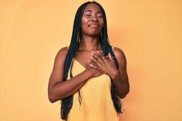 African american woman with braids wearing casual clothes smiling with hands on chest with closed eyes and grateful gesture on face. health concept.