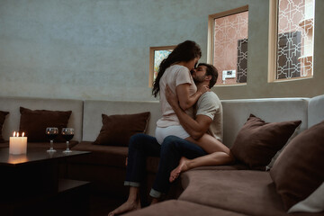 Passion. Young sexy man and woman are kissing before having sex on the couch
