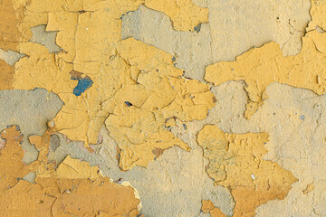 oude afbrokkelende pleister op een gele muur.