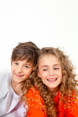 curly haired girl in an orange long sleeve t-shirt sits next to her friend in a white t-shirt