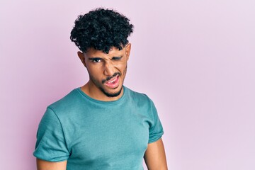 Obraz premium Young arab handsome man wearing casual clothes winking looking at the camera with sexy expression, cheerful and happy face.