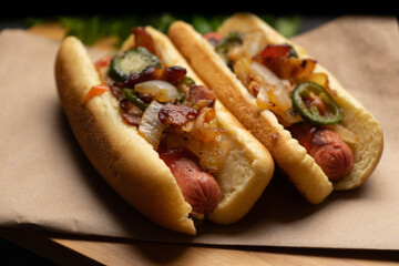 Hot dog with jalapeno pepper, bacon and caramelized onion on dark background