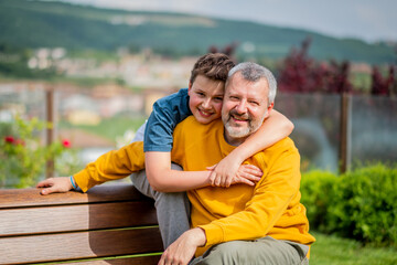 Father and son hug and enjoy together a sunny day in leisure activity on a bench - Father and son hugging are happy