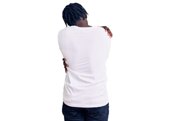 Young african american man with braids wearing casual white tshirt hugging oneself happy and positive from backwards. self love and self care