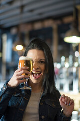 Pretty girl with a beer glass screaming in the pub. Vertical indoors shot.