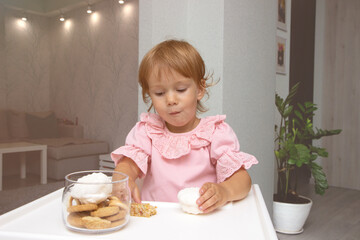 Little girl in kitchen sitting in highchair and eating cookies and candies and sweets together