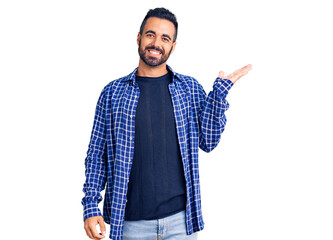 Young hispanic man wearing casual clothes smiling cheerful presenting and pointing with palm of hand looking at the camera.