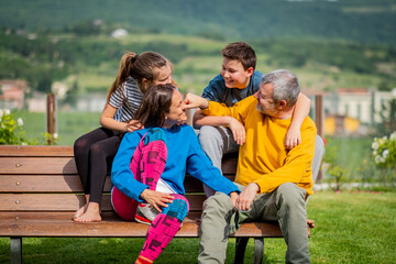 Happy family on the bench - Father, mother, son and daughter enjoying their time together in the countryside
