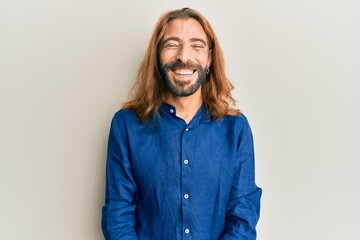 Attractive man with long hair and beard wearing casual clothes with a happy and cool smile on face. lucky person.