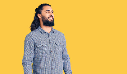 Young arab man wearing casual clothes looking away to side with smile on face, natural expression. laughing confident.