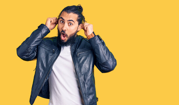 Young arab man wearing casual leather jacket smiling pulling ears with fingers, funny gesture. audition problem