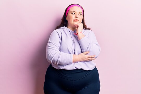 Young plus size woman wearing sportswear thinking concentrated about doubt with finger on chin and looking up wondering