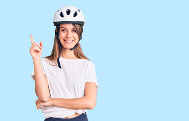 Young beautiful girl wearing bike helmet smiling happy pointing with hand and finger to the side