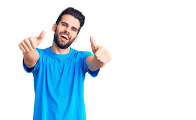 Young handsome man with beard wearing casual t-shirt approving doing positive gesture with hand, thumbs up smiling and happy for success. winner gesture.