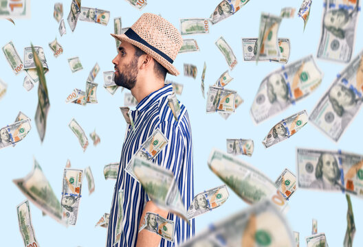 Young handsome man with beard wearing summer hat and striped shirt looking to side, relax profile pose with natural face with confident smile.