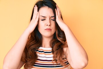Obraz premium Young beautiful brunette woman over yellow background with hand on head, headache because stress. suffering migraine.