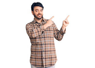 Fototapeta premium Young hispanic man wearing casual clothes smiling and looking at the camera pointing with two hands and fingers to the side.