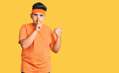 Little boy kid wearing sportswear asking to be quiet with finger on lips pointing with hand to the side. silence and secret concept.