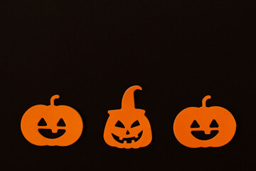 Funny pumpkins orange faces on black background. Happy halloween holiday concept, creative greeting card. Top view, flat lay, copy space.