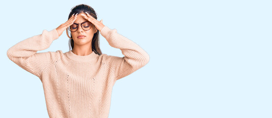 Young beautiful woman wearing casual winter sweater and glasses suffering from headache desperate and stressed because pain and migraine. hands on head.