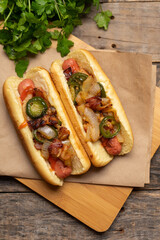 Hot dog with jalapeno pepper, bacon and caramelized onion on wooden background
