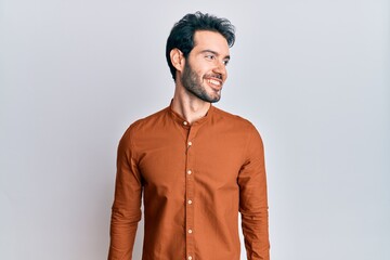 Young hispanic man wearing casual clothes looking to side, relax profile pose with natural face and confident smile.