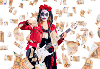 Woman wearing day of the dead costume playing electric guitar with angry face, negative sign showing dislike with thumbs down, rejection concept