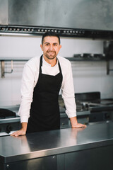 Portrait of a Professional chef posing and wearing uniform and gown in kitchen