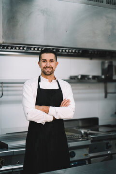 Portrait of a Professional chef posing and wearing uniform and gown in kitchen