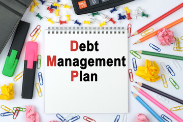 On the table is a calculator, diary, markers, pencils and a notebook with the inscription - Debt Management Plan