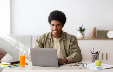 E-learning concept. African American teenager studying online on laptop computer at home